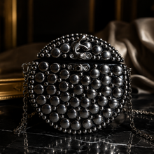 Load image into Gallery viewer, Black beaded clutch bag on a reflective surface with a blurred background